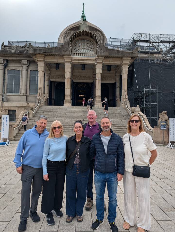 Tour group posing on stone steps of an ornate temple facade