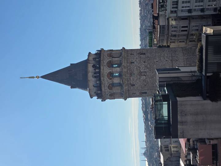 Vertical shot of the historic stone Galata Tower rising above Istanbul’s rooftops.