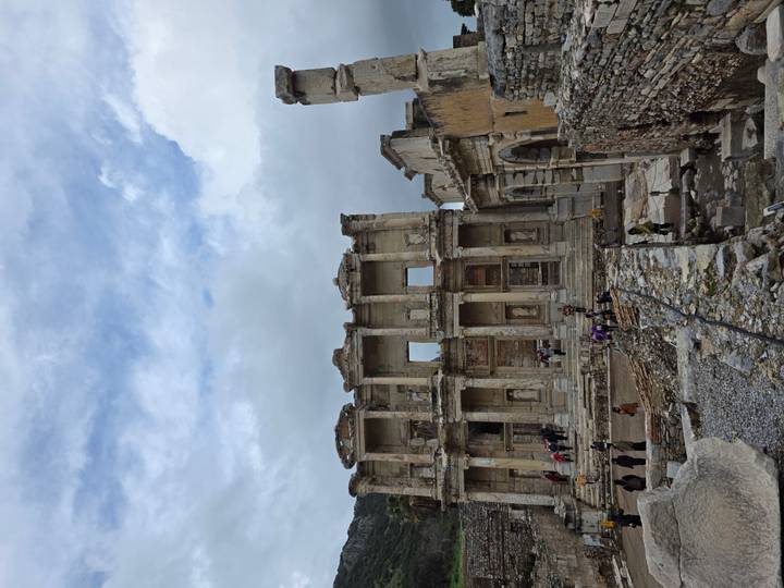 Ancient facade of the Library of Celsus in Ephesus standing against a cloudy sky.