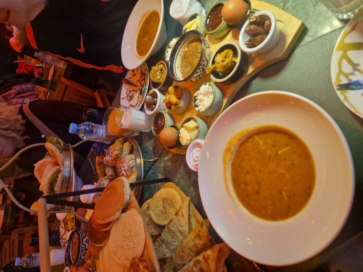 Spread of traditional Moroccan dishes and breads on a busy restaurant table