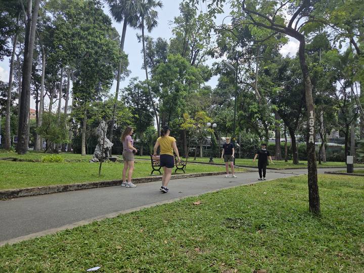 Travelers playing or exercising along a shaded pathway in a green urban park