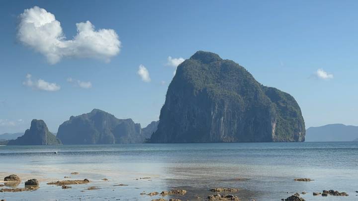 Impressive limestone karst islands rising from calm turquoise sea under clear sky