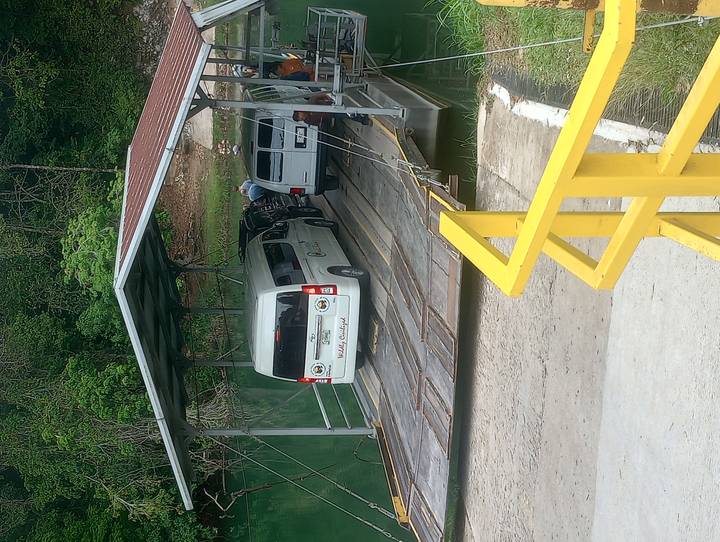 Small vehicular ferry transporting vans across a calm river using a simple roofed platform