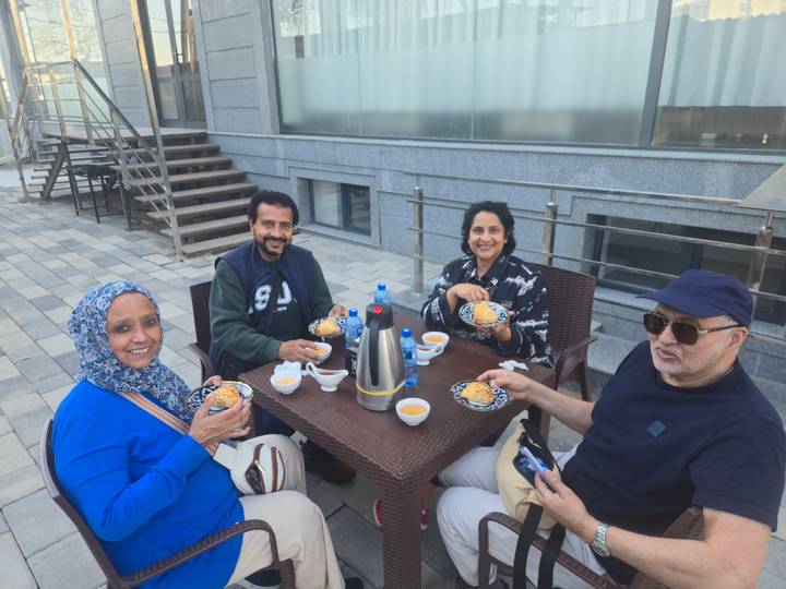 Four friends enjoy tea and pastries at an outdoor rooftop terrace.