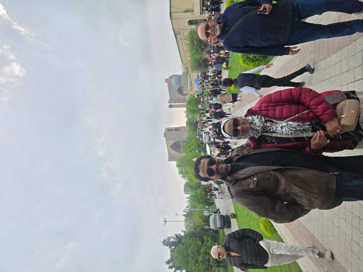 A couple stands on a crowded pedestrian avenue with blue-domed mosque silhouettes in the background.