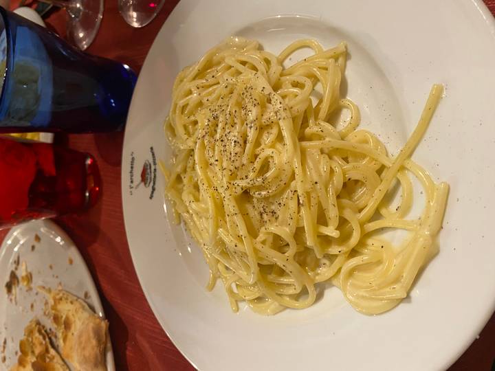 Close-up of a creamy spaghetti dish topped with cracked pepper on a restaurant table