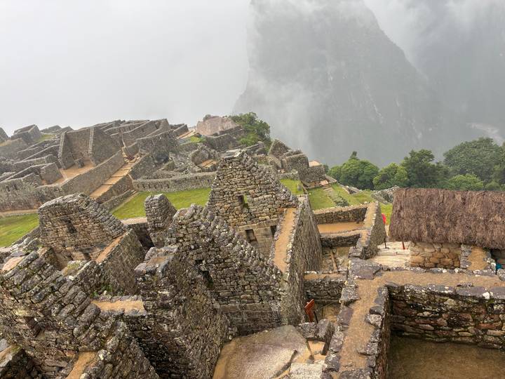 High look-down view of stone foundations and stairways of Machu Picchu against a misty canyon backdrop.