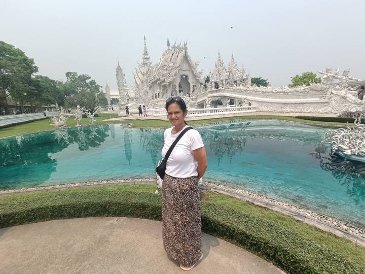 Visitor poses beside the reflective pond at Chiang Rai’s striking white temple, Wat Rong Khun.
