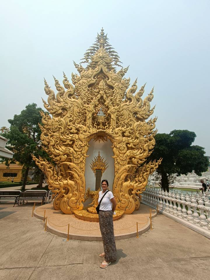 A traveler stands before the ornate golden gateway at the White Temple complex in Chiang Rai.