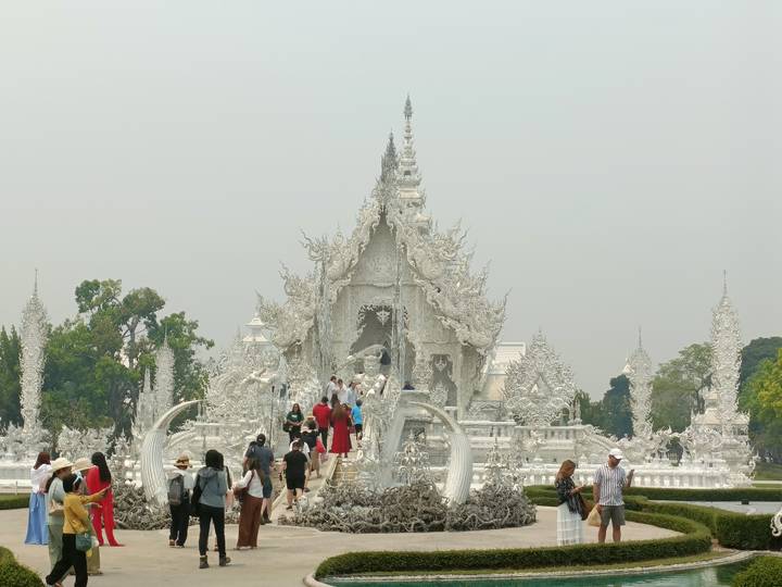 Crowds explore the intricate alabaster buildings of Wat Rong Khun, the famous White Temple.