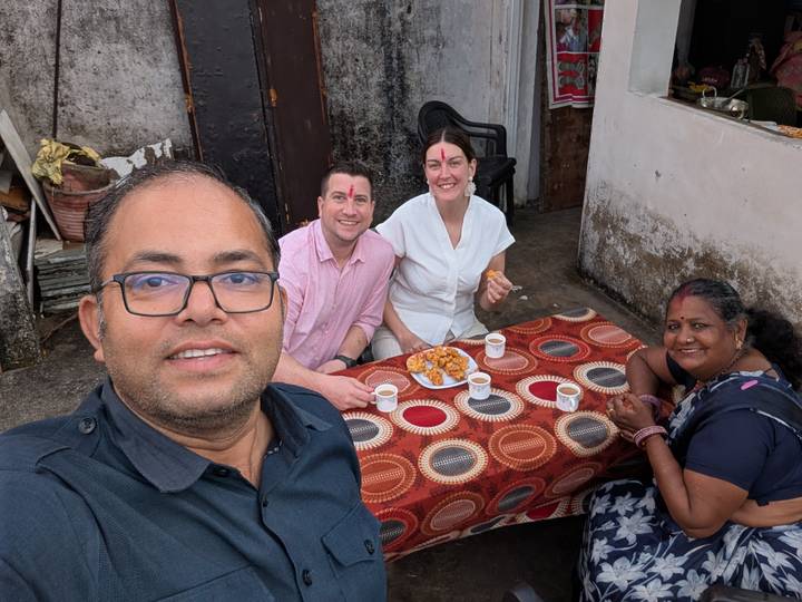 Selfie of guide and three travellers sharing snacks and tea at a colorful outdoor table