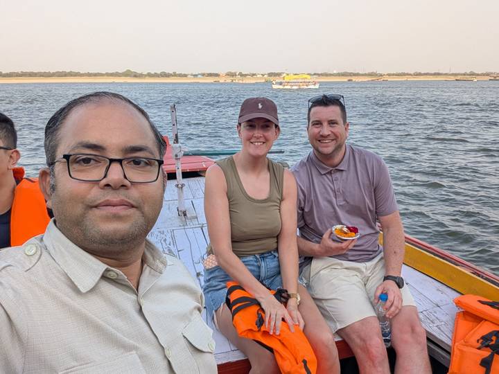 Guide and tourists seated on a small wooden boat cruising a wide river