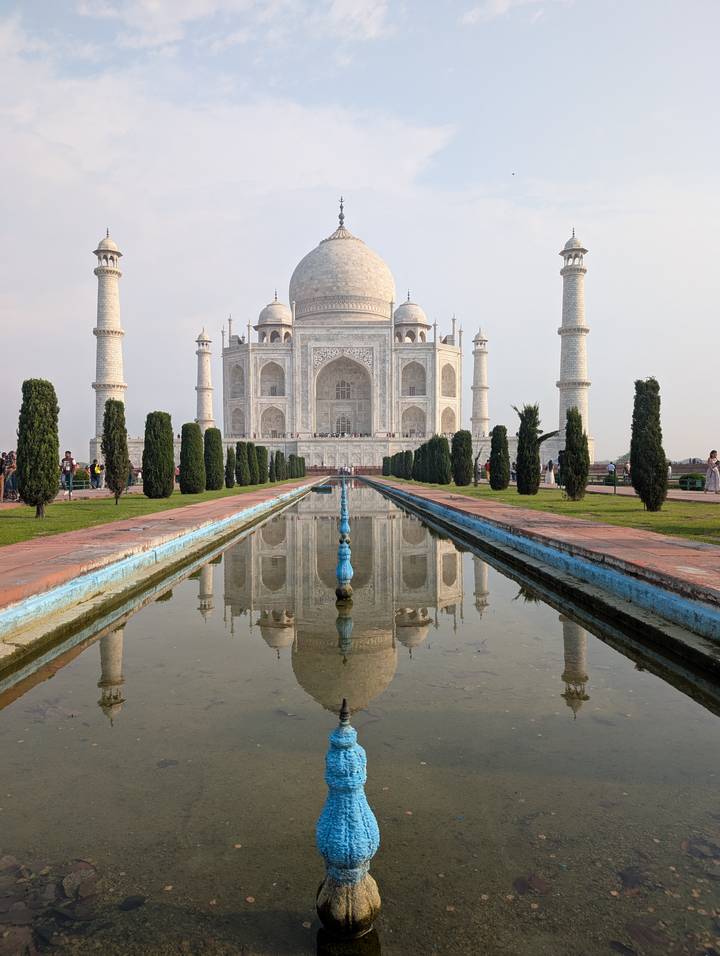 Iconic Taj Mahal reflected perfectly in its long central pool with manicured gardens on a calm day