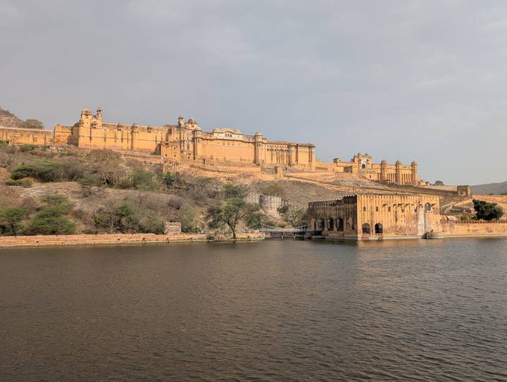 Panoramic view of the honey-colored Amber Fort sprawling along a ridge beside a calm lake