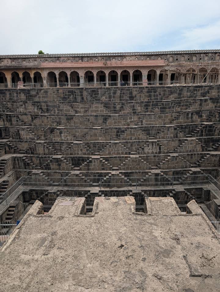 Symmetrical stone steps forming a deep geometric stepwell pattern viewed head-on