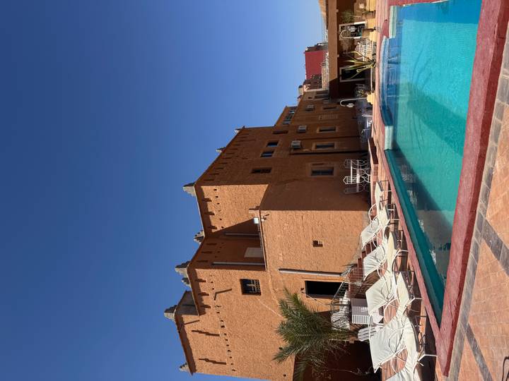 Adobe-style desert hotel with pool and loungers under a cloudless sky