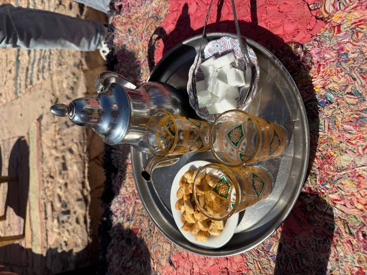 Traditional Moroccan tea service with silver pot, decorated glasses, sugar cubes and snacks on metal tray