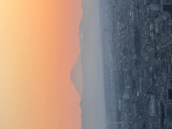 Silhouette of Mount Fuji rising above Tokyo cityscape at colorful dawn.