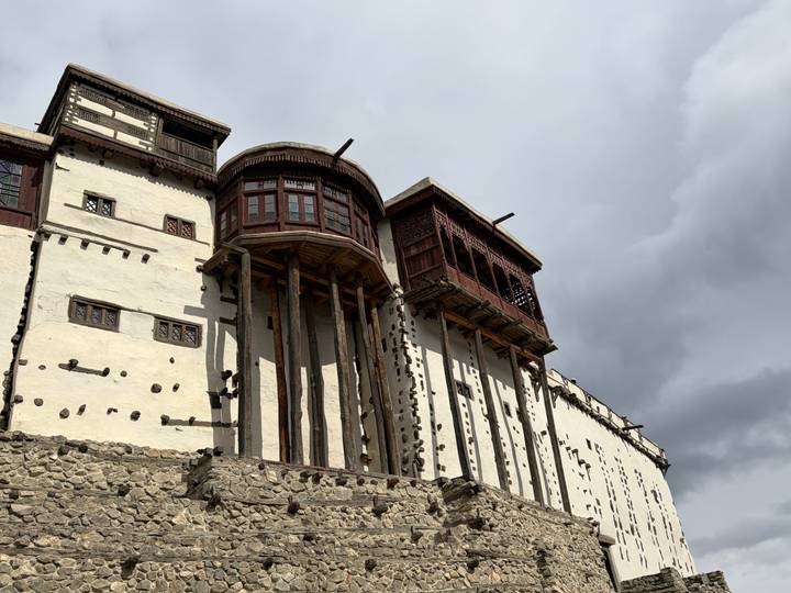Close frontal shot of timber-supported walls and carved windows of historic fort against storm clouds