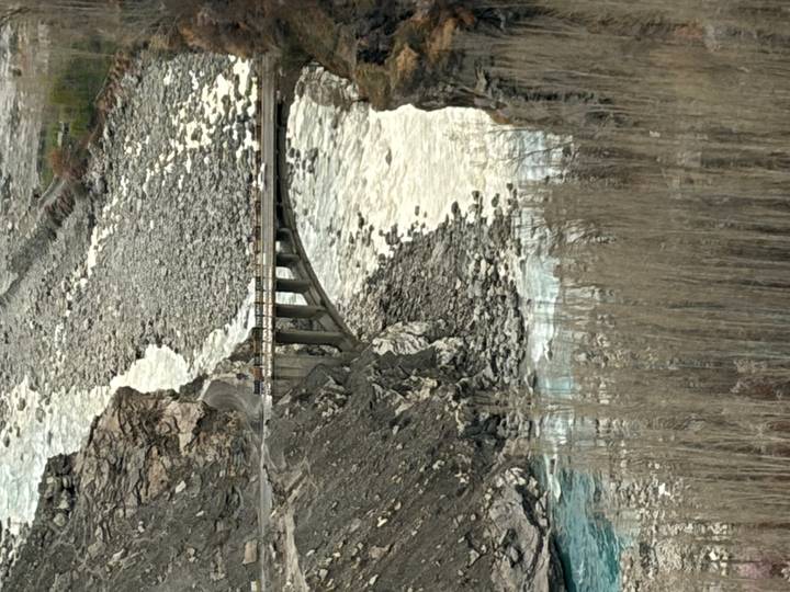 Tall narrow view of concrete bridge crossing turbulent river in rocky gorge