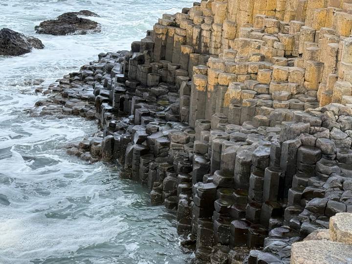 Close-up of the hexagonal basalt columns of the Giant's Causeway with seawater swirling below.