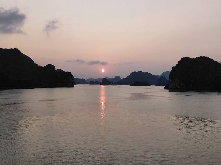 Serene sunset over karst limestone islands reflecting on calm bay waters.