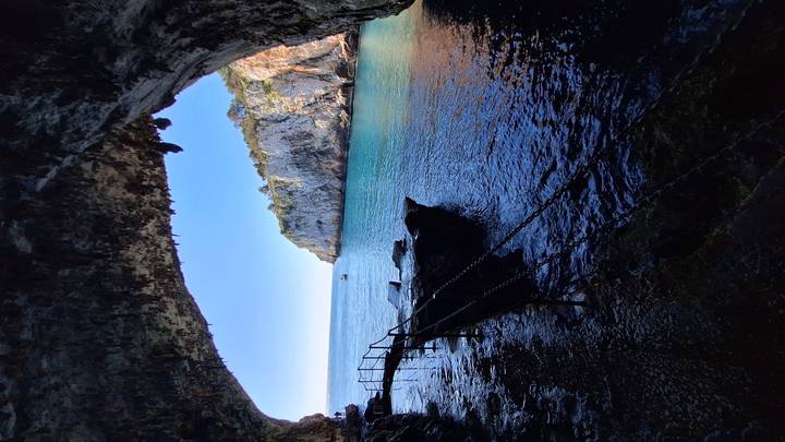A sea cave frames a vivid view of turquoise water and limestone cliffs.