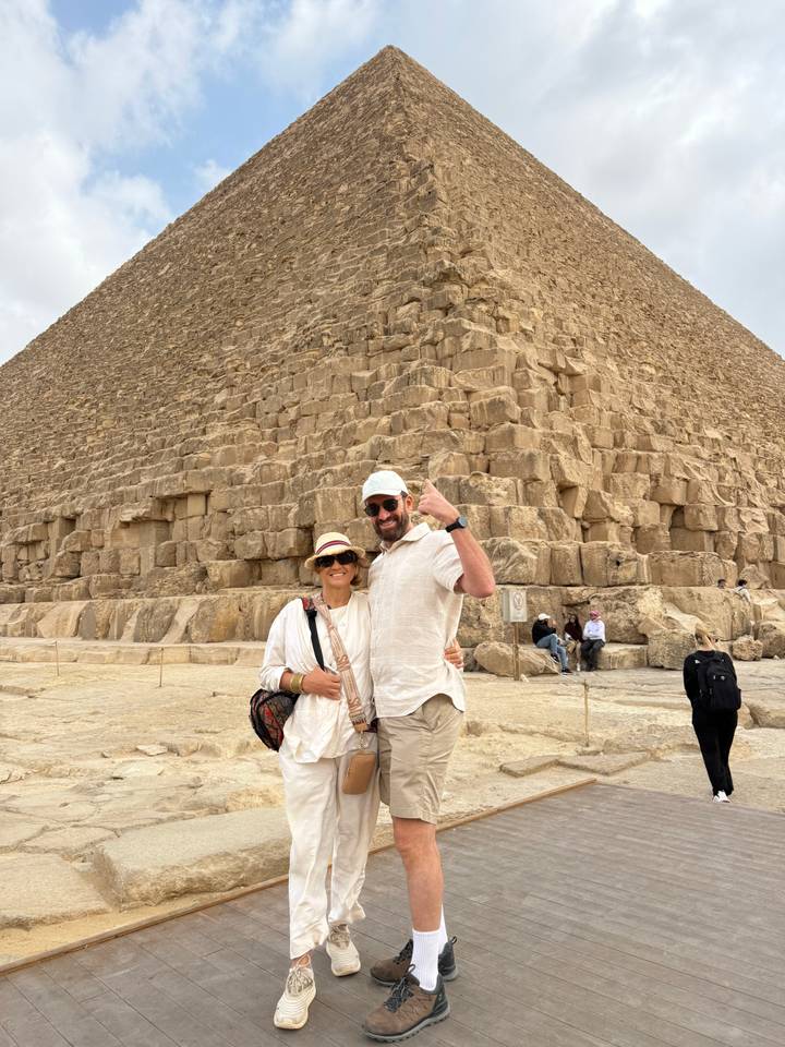 Smiling couple posing in front of the massive stone blocks of the Great Pyramid of Giza