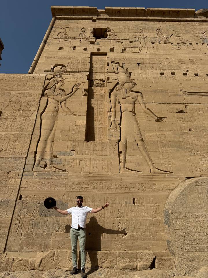 Sunlit stone reliefs of two large ancient Egyptian figures carved into a temple wall
