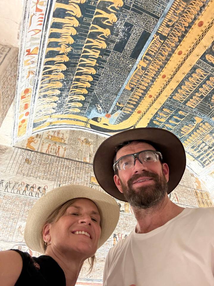 Selfie of travelers beneath colorful hieroglyphic ceiling artwork inside an Egyptian tomb