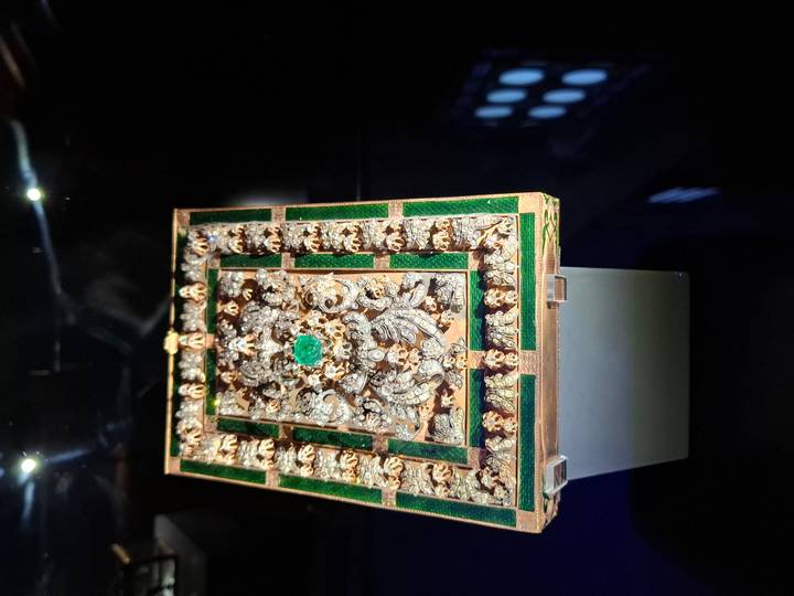 An ornate jeweled box displayed in a dimly lit museum case.