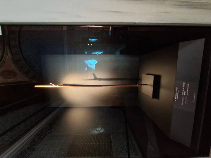 A single historical staff or relic illuminated in a dark display case.