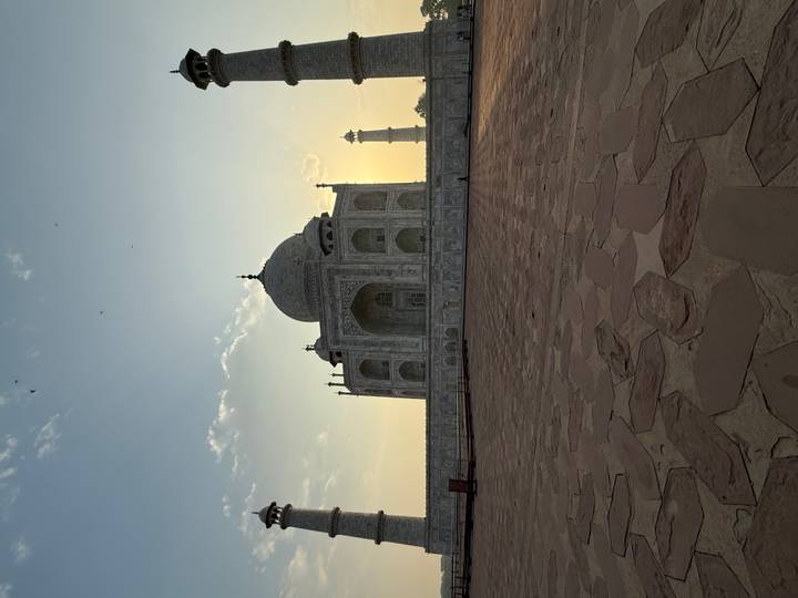 The Taj Mahal silhouetted against a golden dawn sky, viewed from the main forecourt.