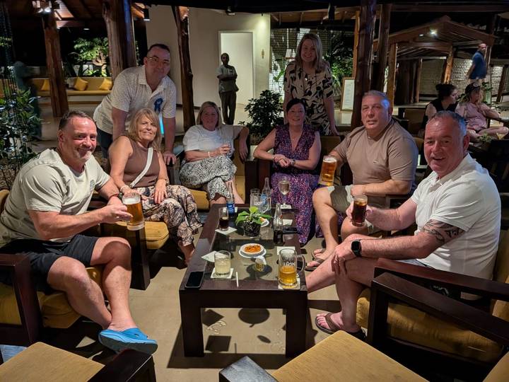 Group of travellers enjoying drinks around a table in a resort lounge at night.