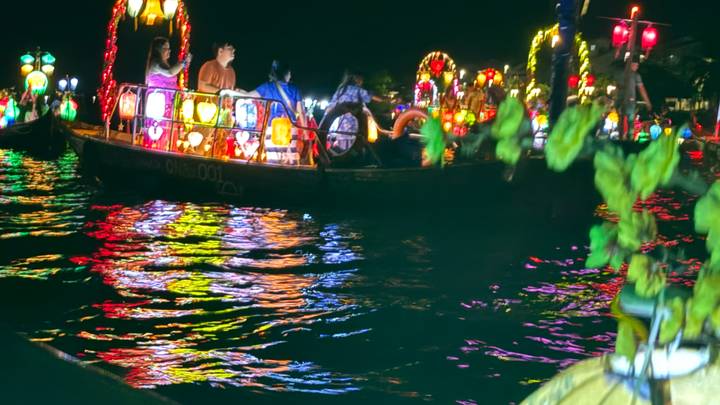 Colorful lantern boats reflecting on water during night festival ride