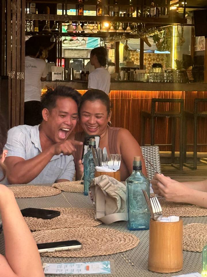 Laughing couple looks at a phone while dining in a warmly lit restaurant