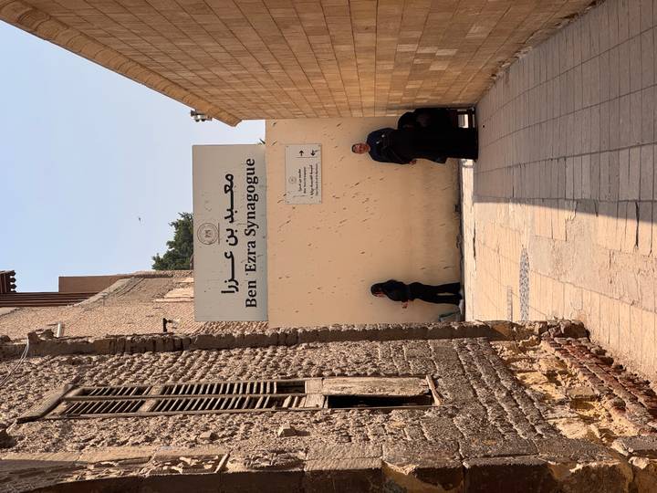 Narrow alleyway leading to the Ben Ezra Synagogue sign with a few locals standing