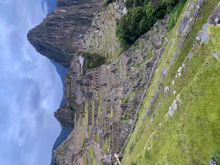 Classic panoramic view of Machu Picchu terraces and Huayna Picchu peak under morning sky.