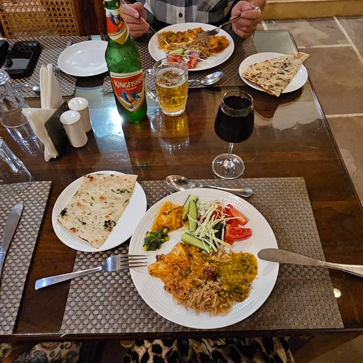 Restaurant table setting with Indian curry, naan, salad, beer and wine ready to be enjoyed.