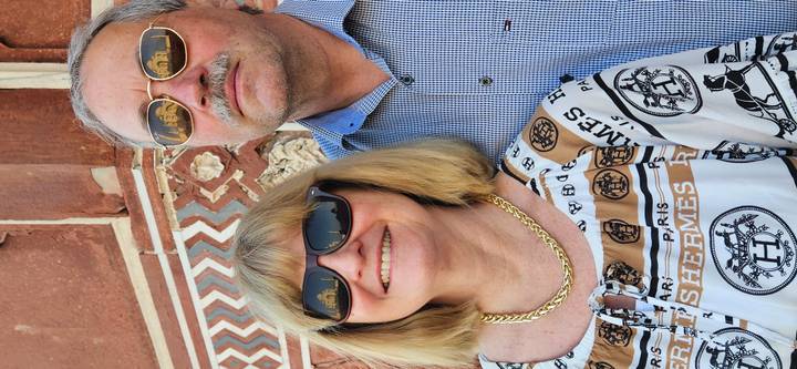 Creative portrait of couple with the Taj Mahal reflected in their sunglasses lenses.