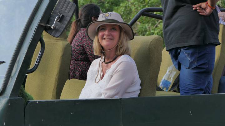 Woman in safari hat smiles from an open jeep seat during a wildlife drive.