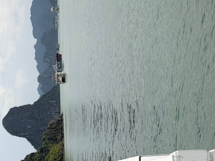 Boats cruise among limestone karsts in the calm waters of Ha Long Bay.