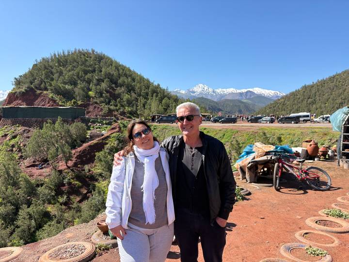 Couple posing together against a backdrop of snowy Atlas peaks and forested hills.