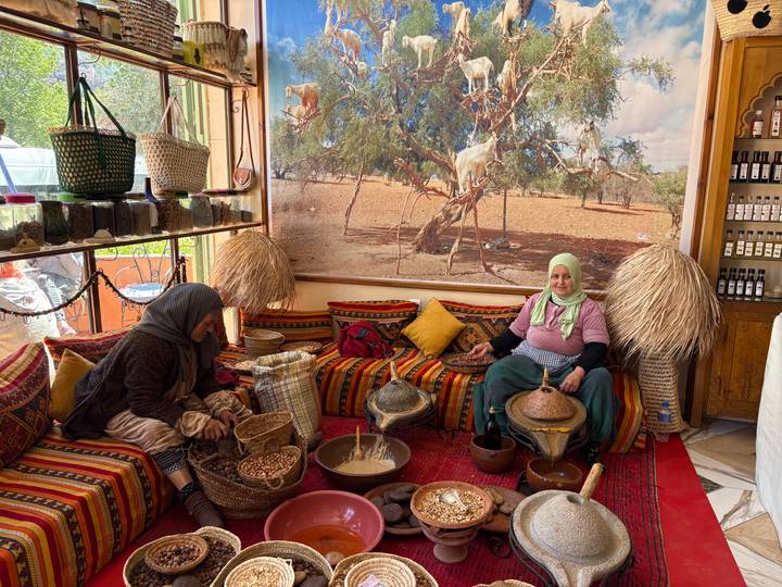 Women demonstrating traditional argan oil production inside a colorful Berber cooperative.