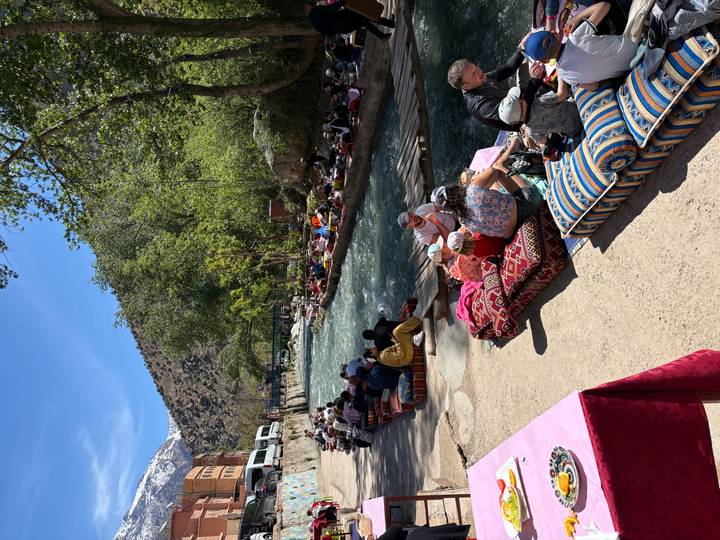 Long riverside dining platforms crowded with locals relaxing beside a clear mountain stream.