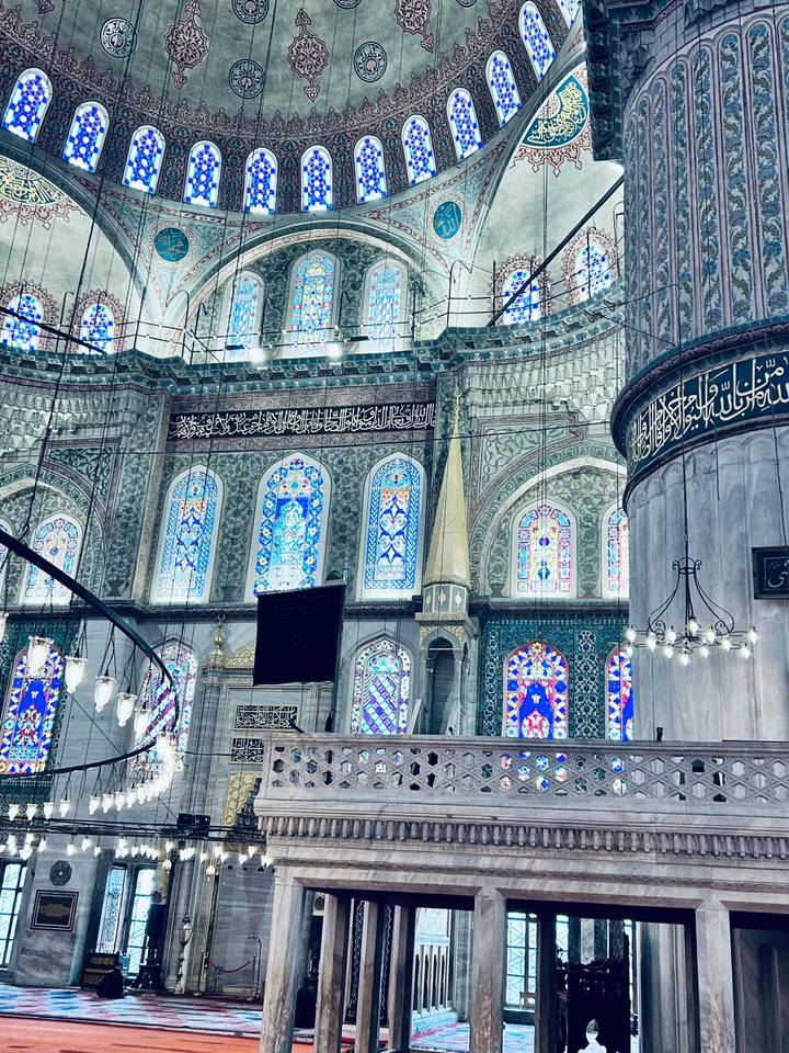 Detailed interior of a historic Istanbul mosque with turquoise tiles and stained glass windows.