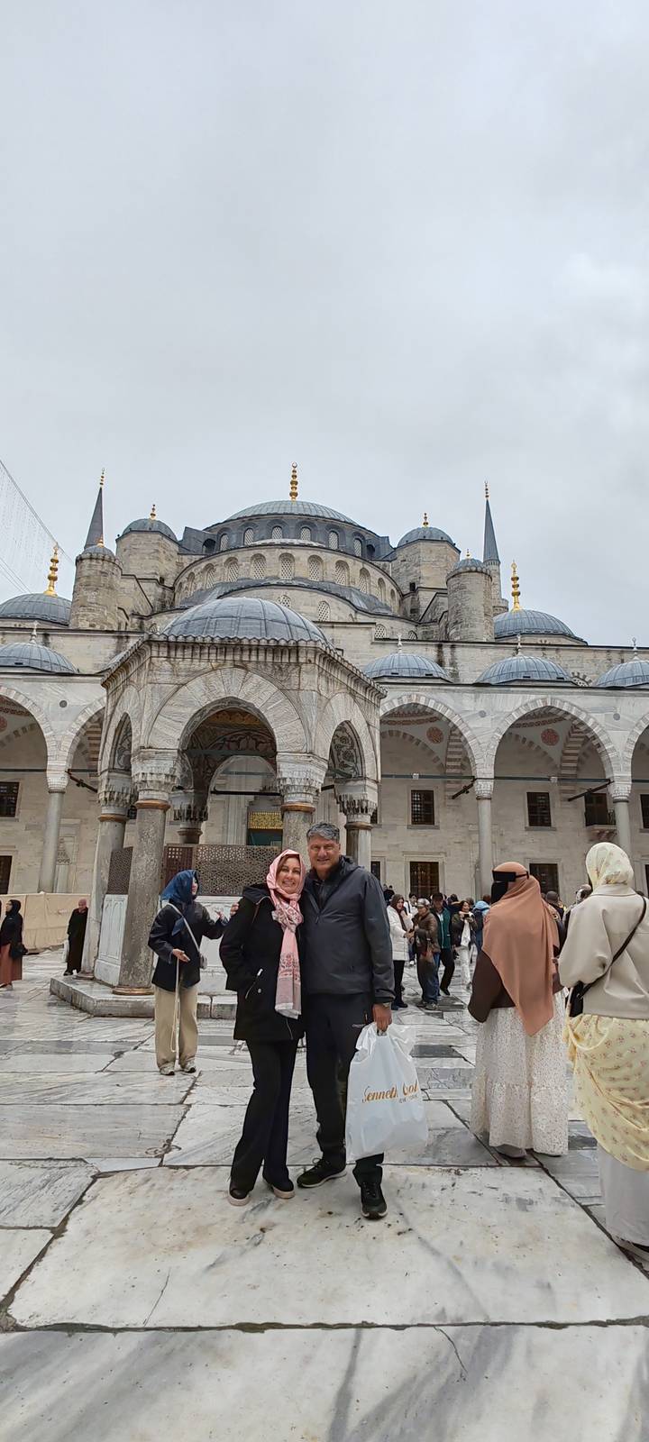 Tourists pose in front of the grand arches of the Blue Mosque courtyard.