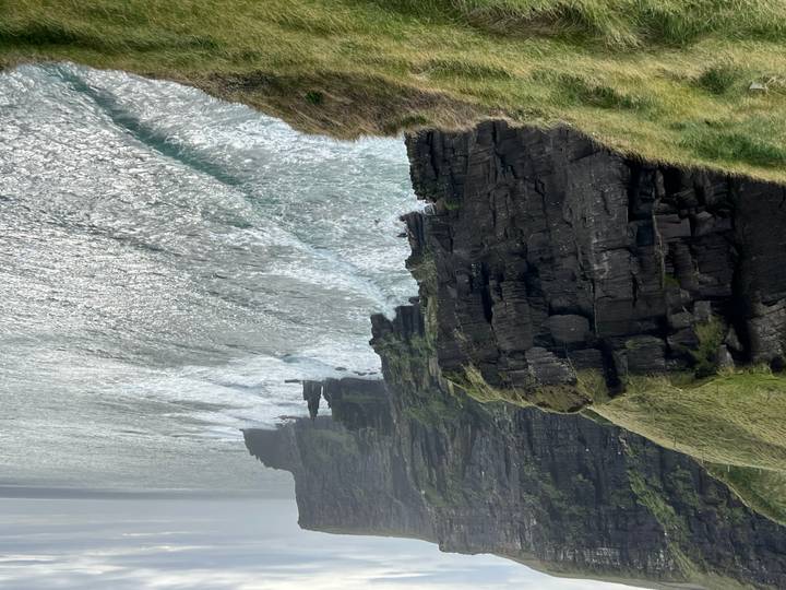 Dramatic cliffs plunge into the Atlantic with waves crashing below.