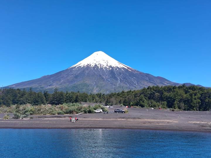 Snow-capped Osorno Volcano rises sharply above forests and a tranquil lake.