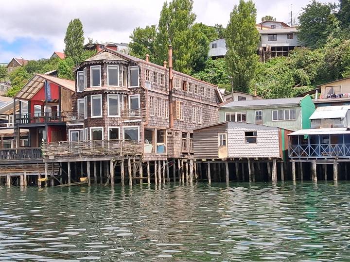 Colourful timber stilt houses line the waterfront reflecting in calm water.